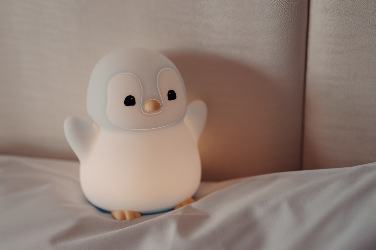 LumiPenguin 企鵝寶寶夜燈擺放於床頭，散發溫柔光線，營造安心入眠的氛圍。