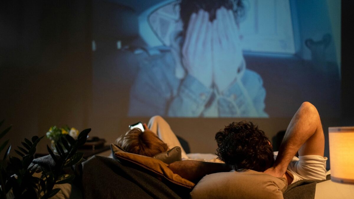 A couple enjoying a romantic movie night at home with a projector and ambient lighting